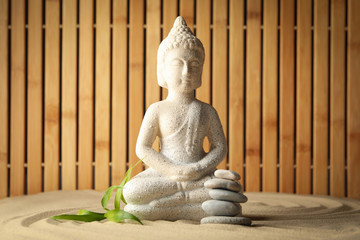 Buddha and leaf on sand background. Zen concept