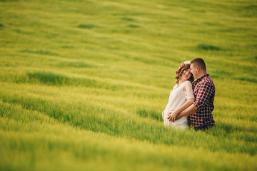 waiting baby. Parenthood. Pregnant young woman and her husband are happy to hold hands, going in the outdoor in the field of green grass background. selective focus.