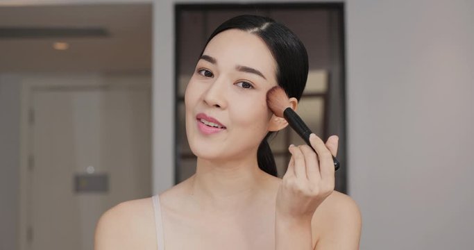 Asian beautiful woman make up her face with happy emotion at home. Confident happy young woman holding mascara apply on eyeleashes.