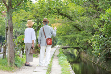 Senior couple walking along riverside footpath