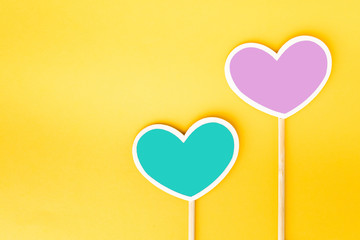 Two heart shaped sticker on yellow background. Empty copy space