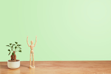 bonsai and wooden drawing mannequin takes care of it, copy space, green gradient background, ideal for ecological and green concepts                                                