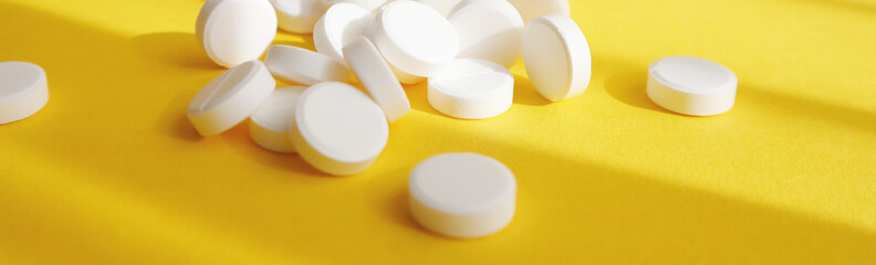 White pills on a yellow background. Banner, close-up. Medicine concept.