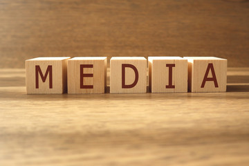 MEDIA word made of wooden cubes on a brown background, business concept.