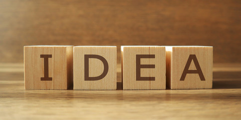 IDEA word made of wooden cubes on a brown background, business concept. Banner.
