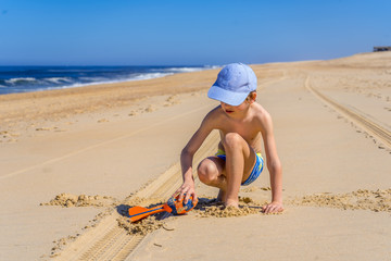 Boy playing on the beach. Activity nature leisure. Happy cheerful boy. Summer vacation concept.