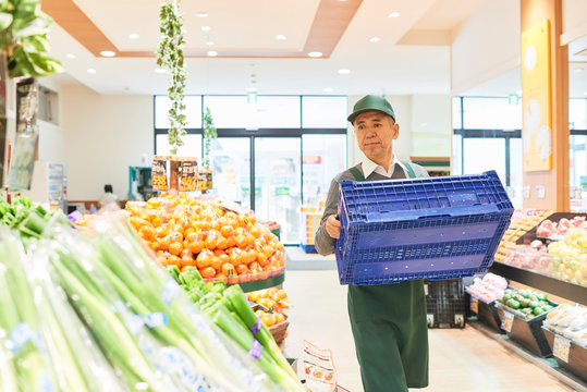Senior man workers arranging produce at supermarket