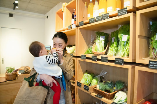 Woman shopping for organic vegetables with baby