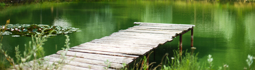 Fototapeta premium Wooden dock, pier, on a lake in summer day. banner