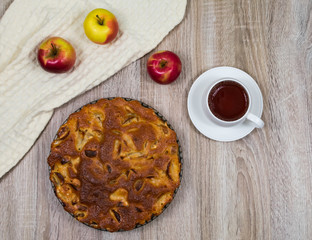 Homemade baked apple pie, in a plate, on a wooden table, ready to eat. View from above.