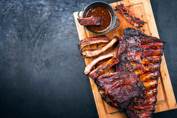 Barbecue veal spare loin ribs St Louis cut with hot honey chili marinade burnt as top view on a rustic wooden cutting board with copy space left - obrazy, fototapety, plakaty