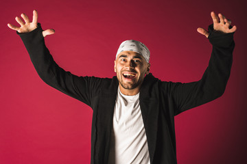 portrait of a nice, funny, crazy, emotional, handsome attractive guy showing various hand gestures dressed in a bright T-shirt in a bow, isolated on red background