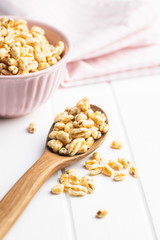 Puffed wheat covered with honey in wooden spoon.