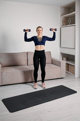 Fototapeta premium A healthy lifestyle. Sporting girl performs exercise with dumbbells at home.