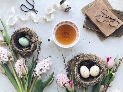 Easter eggs in nests with tea, flowers and books
