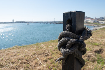 Old, frayed rope tied to wooden post at harbor