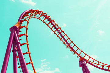 A roller coaster design in orange and pink against a blue sky.