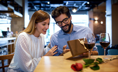 Birthday present for a girlfriend. Romantic couple sitting in the cafe and drinking red wine. Dating, love, relationships
