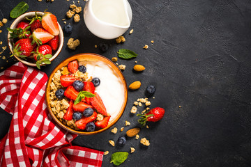 Fototapeta na wymiar Greek yogurt granola with fresh berries on black stone table.