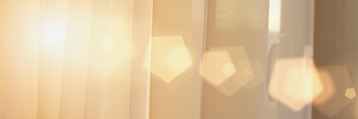 ray of sun shining on light room through fabric curtain
