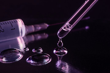 Close-up on a pipette leaving few drops of fluid on glass surface