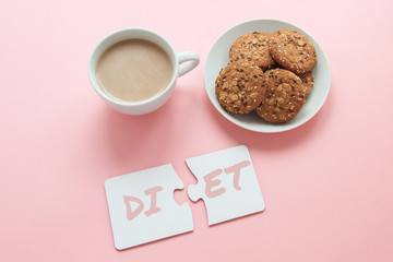 two white disconnected puzzles with the inscription diet, a cup of coffee and a plate with cookies 