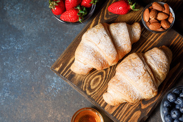 Breakfast with fresh croissants and berries on dark table background