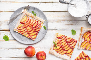 Refreshing delicious dessert, juicy nectarine puff pastry tarts with cream cheese and sprinkled with powdered sugar