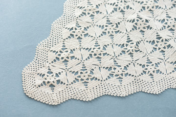 White handmade lace isolated on the blue background. Crocheted accessory. Crafts and Hobbies for women. 