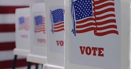 CU straight on row of voting booths at polling station during American election. US flag in...