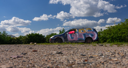 Devastation - a car standing in a closed parking lot, painted in graffiti.