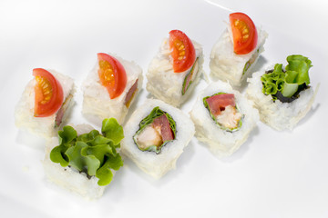 Japanese Caesar roll made from rice, cherry tomato, chicken, lettuce, Parmesan cheese and Caesar sauce on a white plate