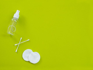 hygiene, spa and beauty concept. Cotton pads, swabs, ear sticks and tonic on green background.