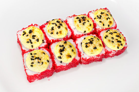 Japanese Yuki roll of rice, shrimp, red tobik, cream cheese, squid, white sauce and sesame seeds on a white plate