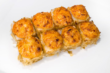 Japanese roll of rice, cream cheese, eel, cucumber, tuna chips, parmesan cheese, spicy sauce on a white background