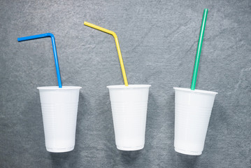 White plastic cups with drinking straw on the table flat lay background.