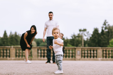 Handsome young father and beautiful mother in sunny summer nature playing with their cute small childrens