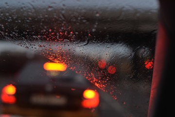 Side lights of cars in front through a rain-filled windshield in the night 