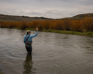 A man teaching a boy how to fly fish on a western trout stream.