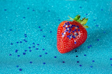 Ripe strawberries in sparkles in the shape of stars on a blue shiny background. Selective focus, copy space.