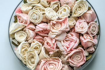 artificial roses light pink in a dish on a colored background
