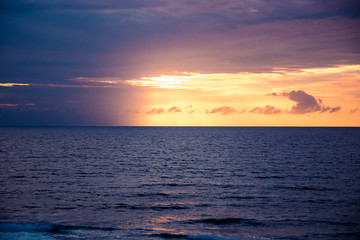 Sea beach surf waves Bali landscape Uluwatu surfing spot sunset scenery with cliff view on sea horizon with sunset sky with purple orange clouds with curly clouds as tropical island background