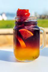 Refreshing cold sangria or punch with fruits in glasses in street cafe during hot day