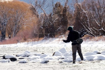 Man fly fishing in winter and casting on the Roaring Fork River, Carbondale, CO