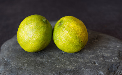 Two limes on a slate against a grey background 