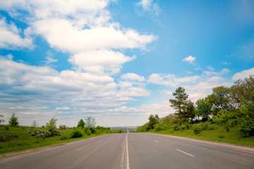 Fototapeta premium Open road through the green field and clouds on blue sky in summer day