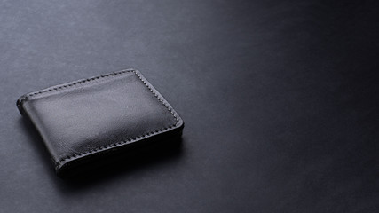 Black leather wallet on black texture background, desk from top view, copy space.  - obrazy, fototapety, plakaty