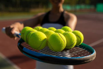 jeune femme montrant des balles de tennis sur une raquette