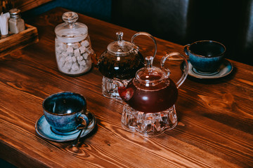 cups and teapots on a wooden table and sugar cubes