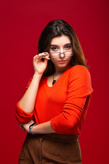 Young girl student or business woman girl in glasses with swith a pensive expression on a red background